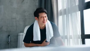 এক ব্যক্তি পেটে হাত দিয়ে দাঁড়িয়ে আছেন এবং তার পাকস্থলী ও অন্ত্রের একটি জ্বলজ্বলে চিত্র দেখা যাচ্ছে।