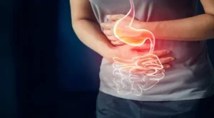 ছবিতে একজন ব্যক্তিকে তার পেটের ওপর দুই হাত রেখে অস্বস্তি অনুভব করতে দেখা যাচ্ছে। তার পেটের ওপর পাকস্থলীর একটি রেখাচিত্র বা গ্রাফিক যুক্ত করা হয়েছে, যা গ্যাস্ট্রিক বা পাকস্থলীর ব্যথার সমস্যাকে নির্দেশ করে।