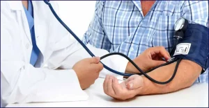 একজন ডাক্তার রোগীর রক্তচাপ পরিমাপ করছেন।