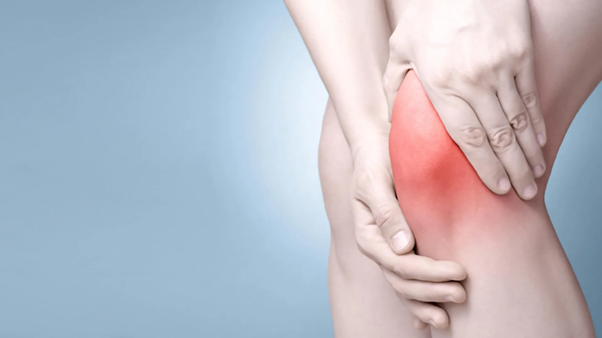 একজন ব্যক্তি তার ব্যথাতুর লালচে হাঁটু ধরে আছেন।