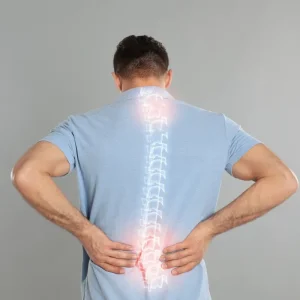 Back view of a man in a blue polo shirt with a semi-transparent graphic of a human spine overlaid on his back. Red glowing highlights on the upper and lower sections of the spine indicate areas of pain, inflammation, or injury.