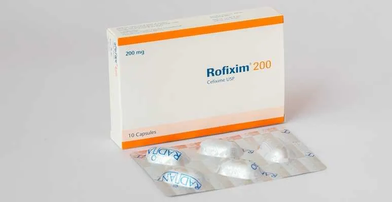 A white and orange box of Rofixim 200 (Cefixime USP) 200 mg medication sitting next to a silver blister pack of capsules.