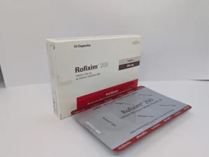 A white box and a silver blister pack of Rofixim 200 capsules, an antibiotic containing 200 mg of Cefixime, displayed against a plain white background.