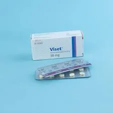 A white and blue medication box for Viset 50 mg placed behind a silver blister pack containing small white round tablets, all set against a solid light blue background.