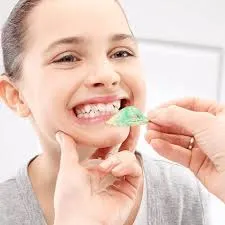 একজন ডেন্টিস্ট একটি ছোট মেয়ের দাঁতের ইম্প্রেশন বা ছাঁচ পরীক্ষা করছেন।