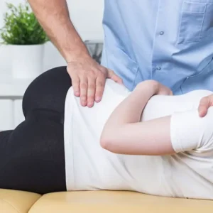 A professional physiotherapist performing manual therapy and spinal mobilization on a patient to relieve back pain and improve mobility.