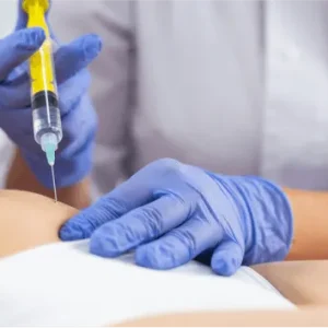 A medical professional in blue gloves administering a targeted syringe injection into a patient's midsection.